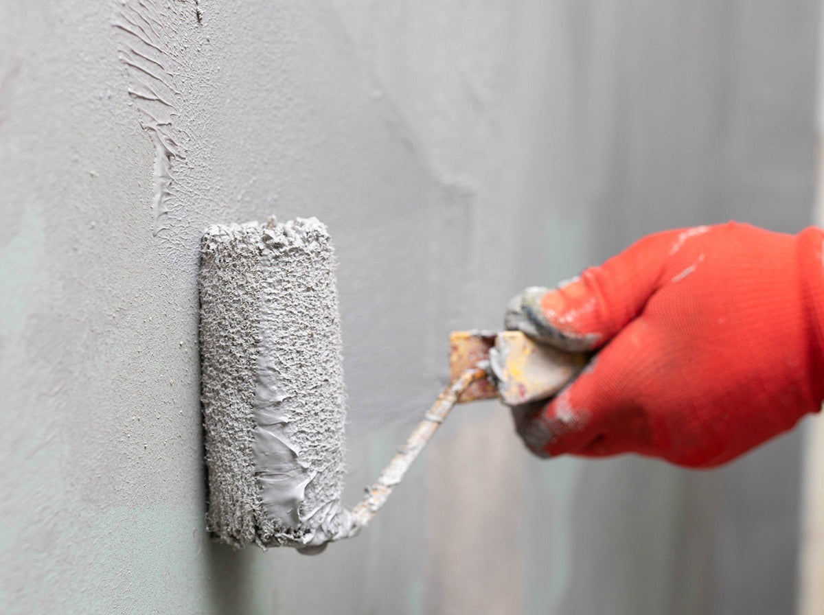 grey paint roller being applied to wall