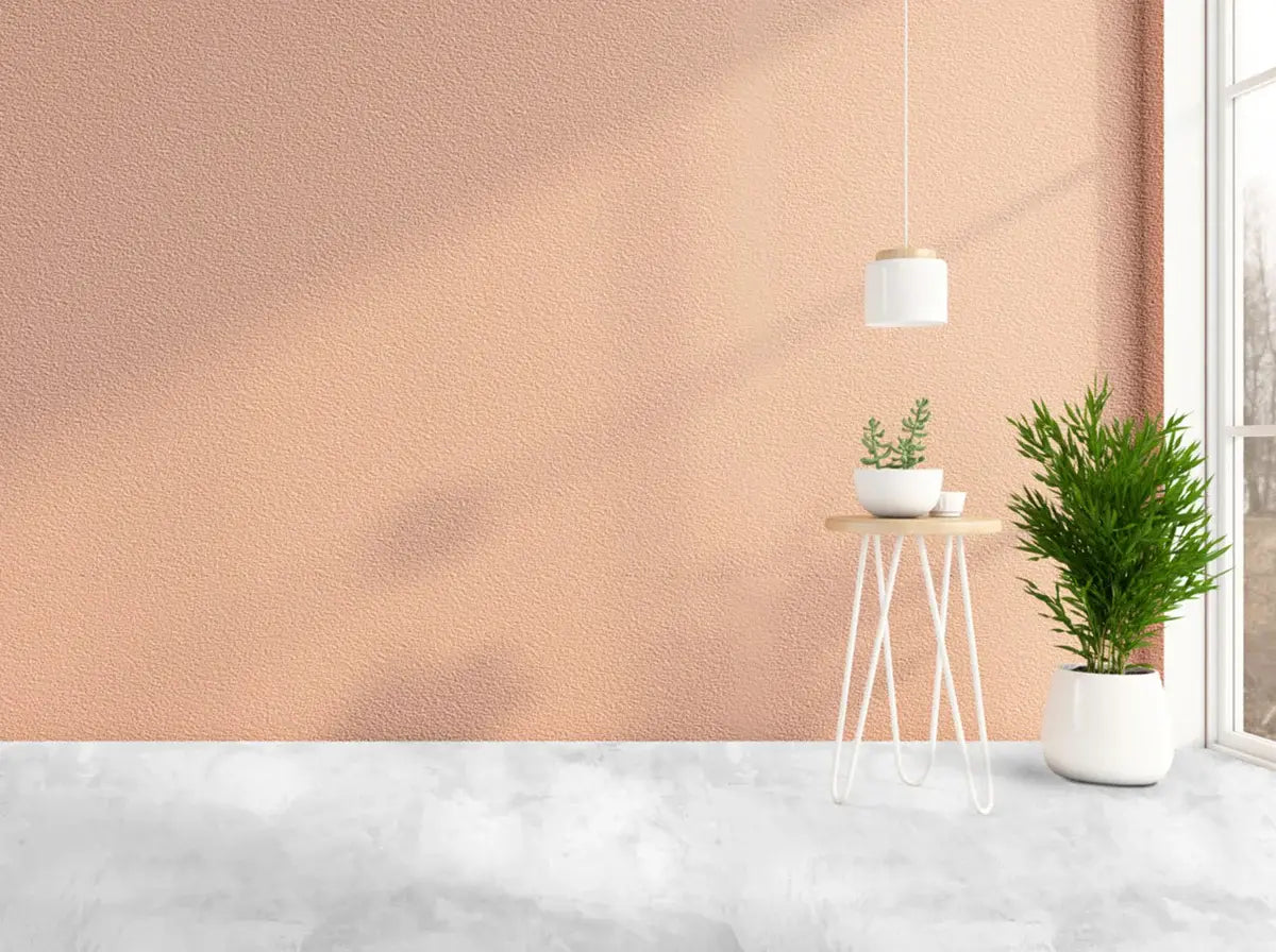 Modern interior with a pink wall, white table, and potted plants.