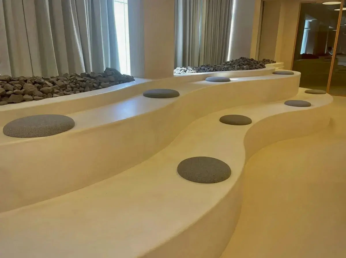 Modern indoor landscape with curved concrete wall and circular stone platforms.
