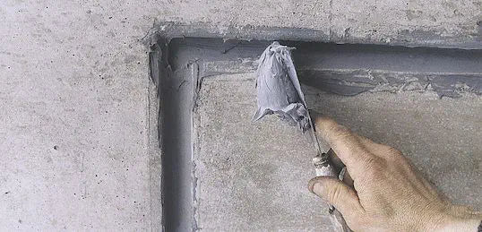 a trowel applying diaseal to a concrete wall