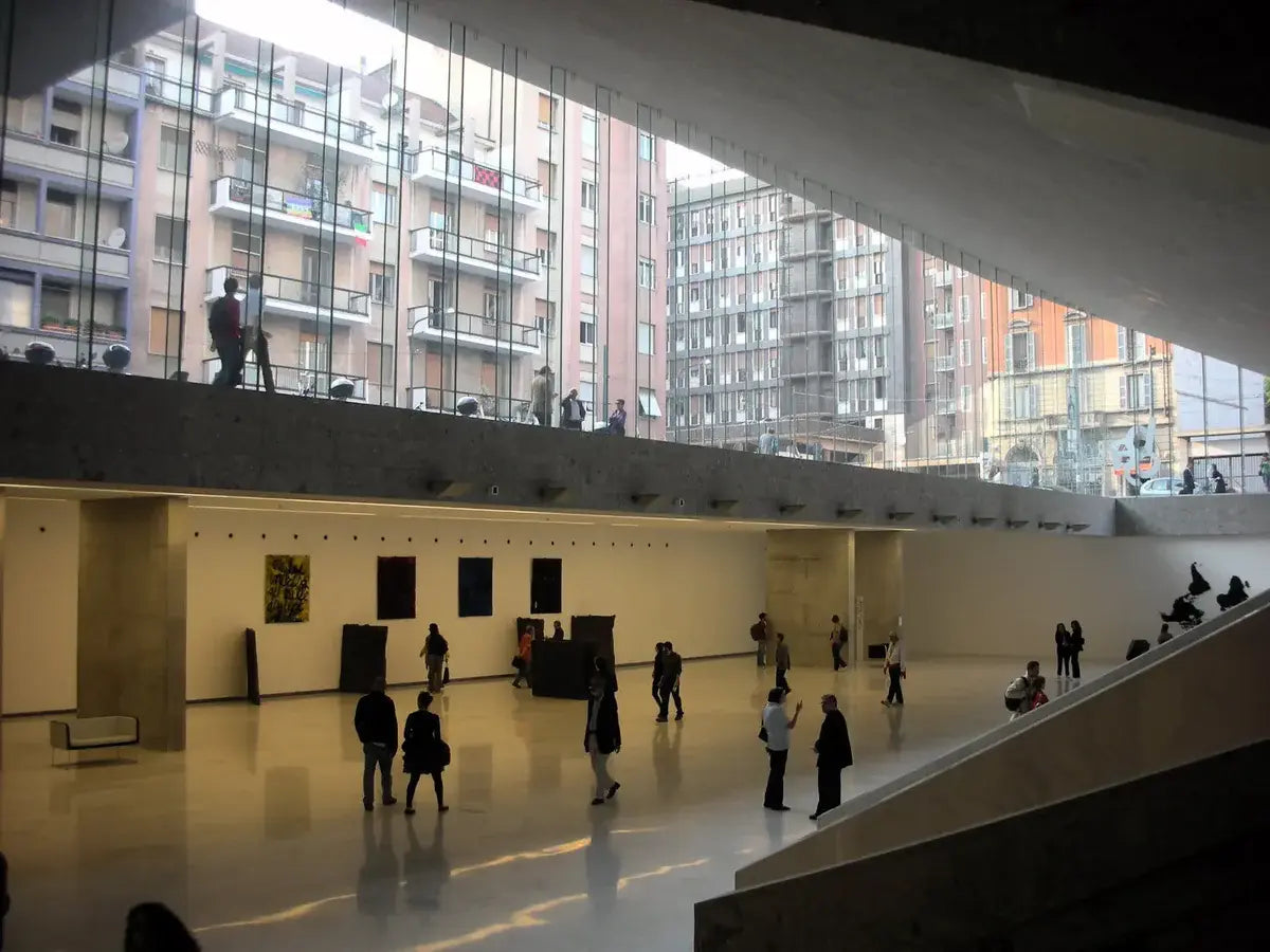 Modern architectural interior with people walking and a cityscape view through large windows.