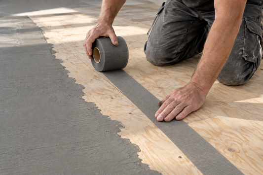 Fine gray mesh being applied over a plywood floor seam