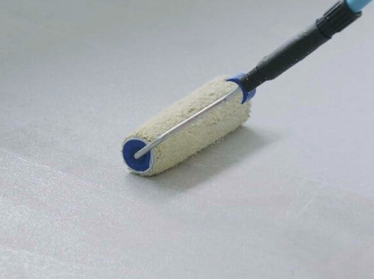 A paint roller being used on a surface, applying Grip Primer.