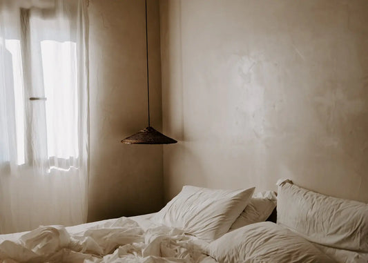 Bedroom with tousled bed and light filtering through curtains