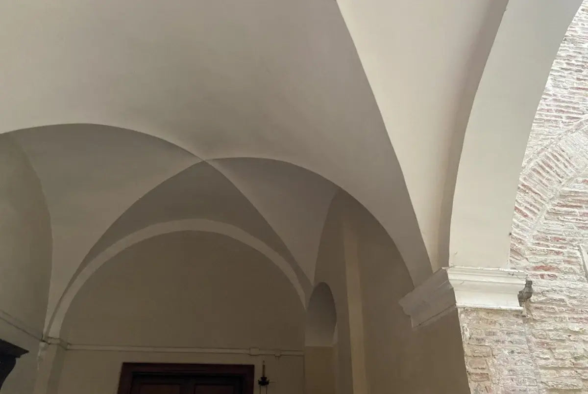 Architectural detail of a building with white arches and brick walls.