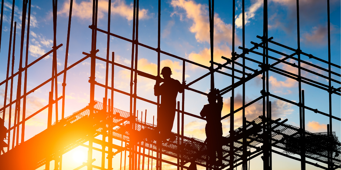 Construction workers on scaffolding with sunset in background