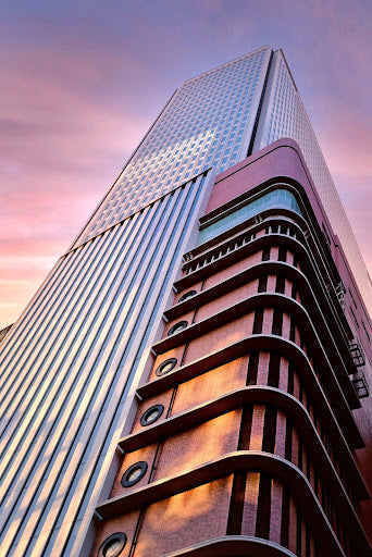 A massive skyscraper building looms above as the sun sets.