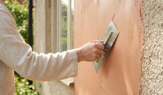 Trowelling Argacem Coloured stucco onto an exterior wall