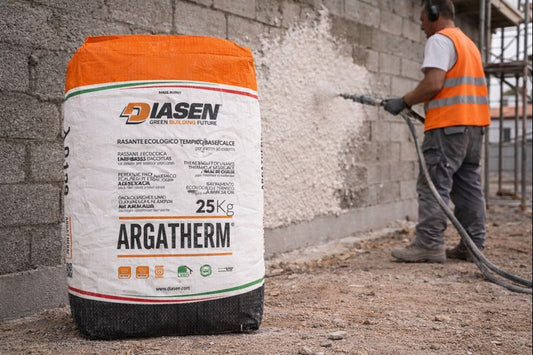 Spray-applying Argatherm skim coat on a block wall, 25 kg bag in front