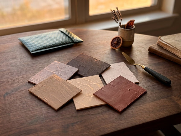 Wooden surface with leather samples and a knife, near a window.