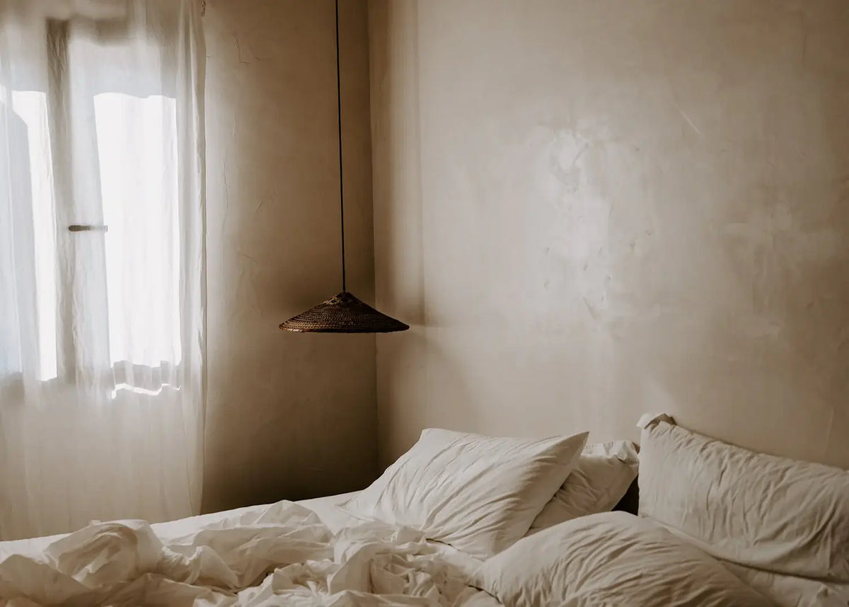 Bedroom with tousled bed and light filtering through curtains